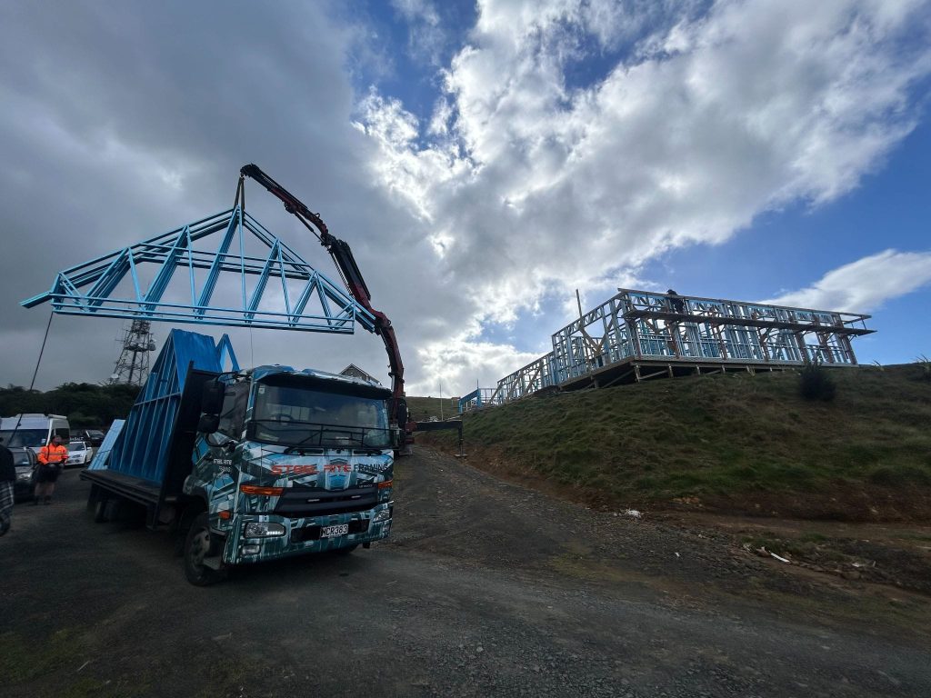 A truck is moving with a crane and a steel framing structure