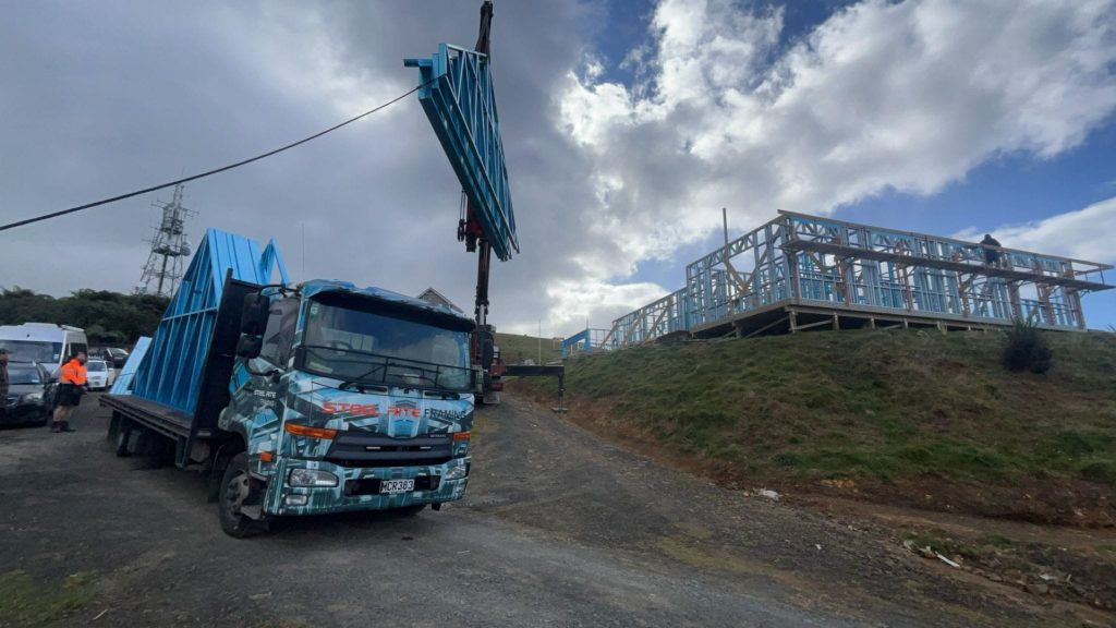 A truck is moving with a crane and a steel framing structure